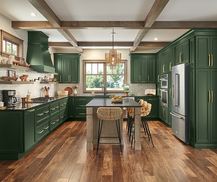 modern kitchen with deep green cabinetry, a contrasting dark countertop, and wooden beams on the ceiling