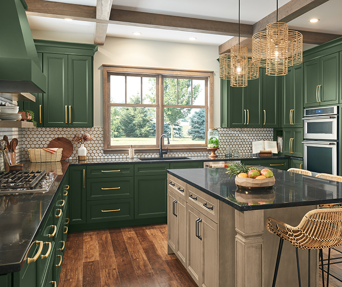 bright kitchen with deep green cabinetry, gold hardware, and a contrasting light gray island