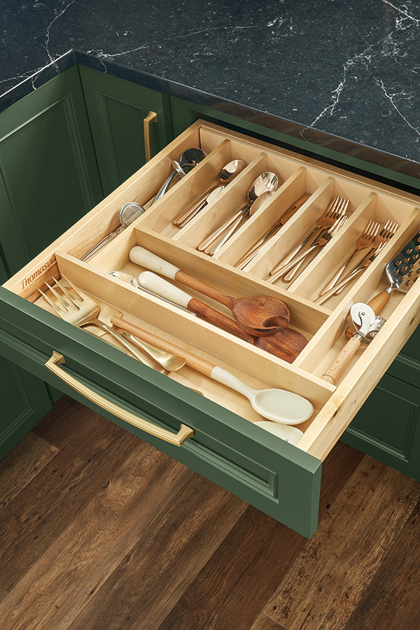 Close-up of a green Thomasville kitchen drawer with a wooden base cutlery insert, organizing utensils and kitchen tools, providing efficient storage in a modern kitchen.