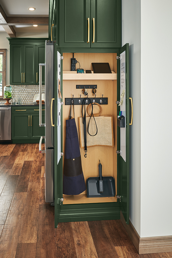 View of a utility drop zone inside a deep green Thomasville Cabinet, featuring hooks and storage for organizational tools and accessories.